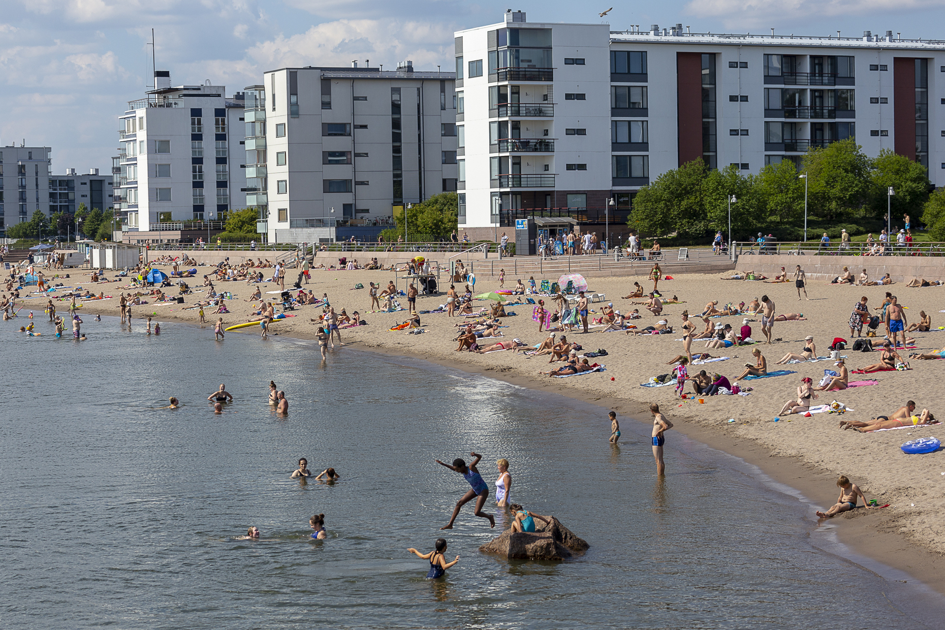 Aurinkolahden uimaranta aurinkoisena kesäpäivänä, taustalla kolme kerrostaloa.